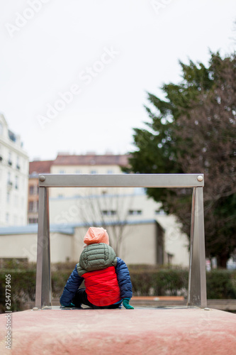 Kind alleine auf Spielplatz in Stadt. Kid alone on playground in city.