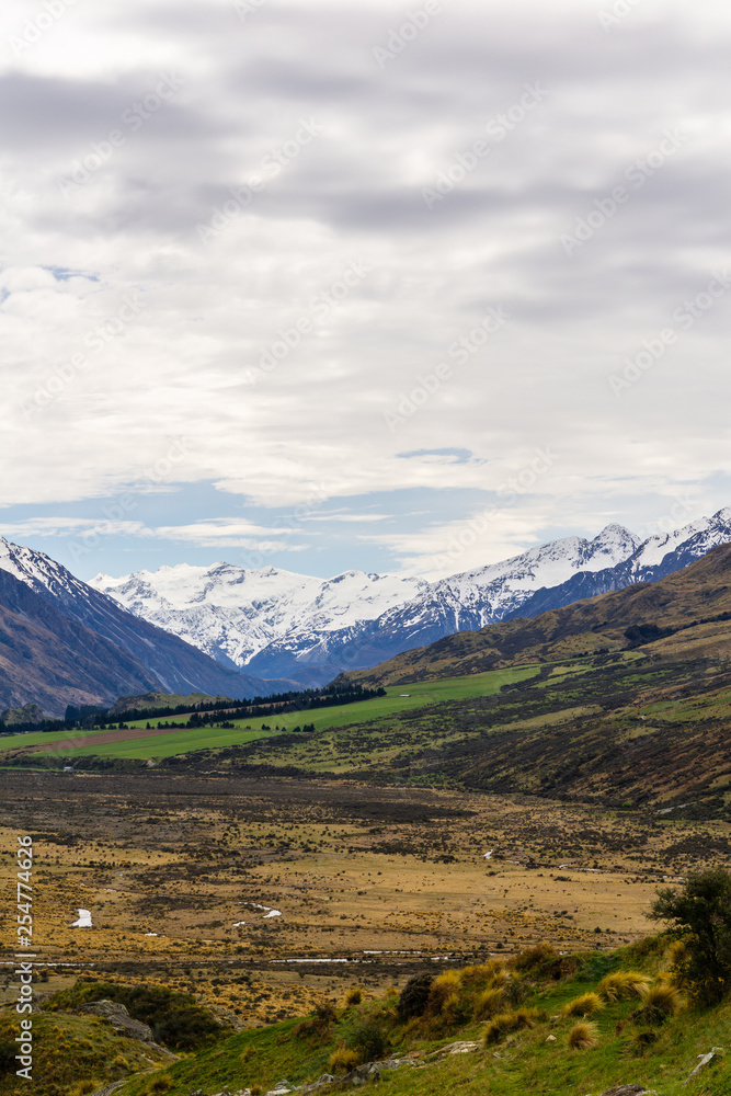 Beautiful vast valley with mountains on the horizon, snowy mountain peaks, during sunny with dramatic sky