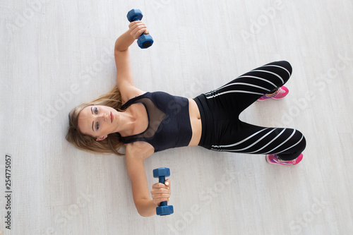 Sport woman lying on floor doing the exercise in sport style clothes. Beautiful young sporty fitness model