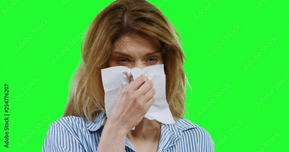 Close up of the Caucasian ill woman with fair hair blowing her nose as having cold on the green screen background. Alpha channel. Close up of the Caucasian ill woman with fair hair blowing her nose as having cold on the green screen background. Alpha channel.