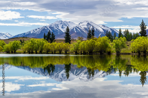 Symmetrical landscape due to reflection in a lake, trees and mountain range reflecting in a lake