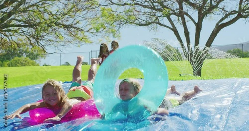 Kids summer water slide fun, two smiling boys sliding down waterslide