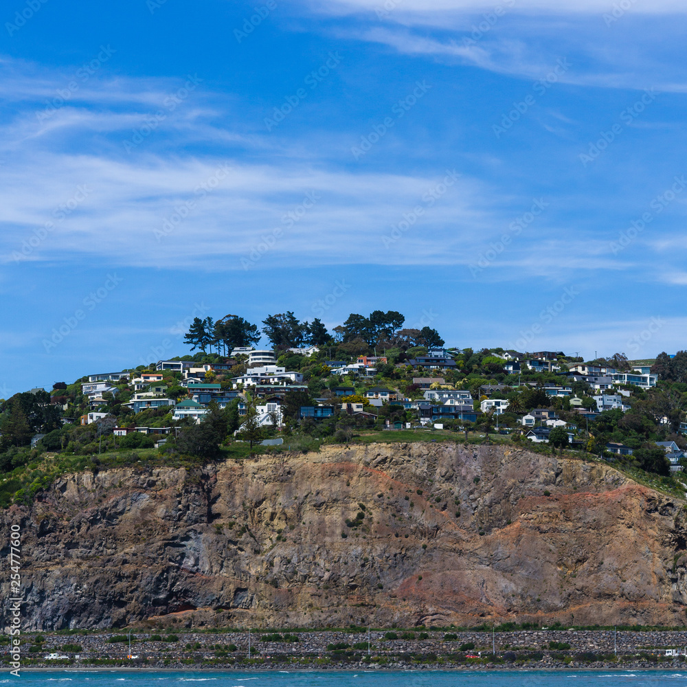 Coastal town on a steep rocky hill during sunny day with blue sky