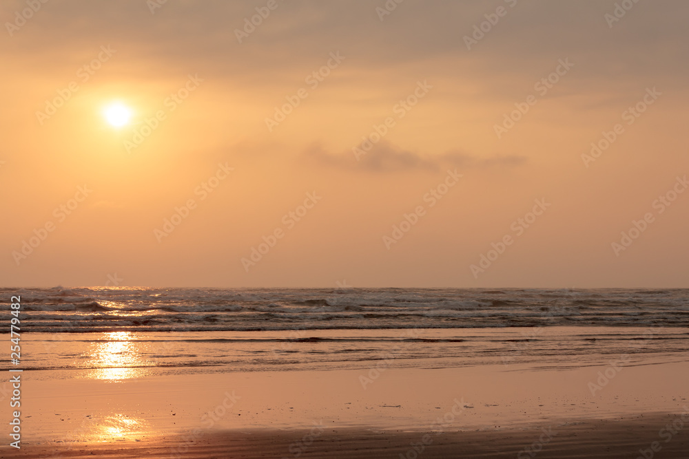 orange sky with sunset over water and sand along the pacific ocean
