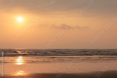 orange sky with sunset over water and sand along the pacific ocean © Taya