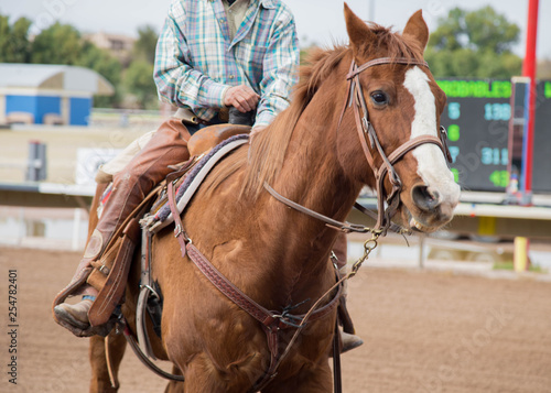 man horseback riding on a brown horse on a race track. 