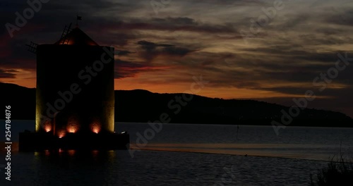 Timelapse stunning colors, An ancient windmill with romantic lights on the sea bay at sunset