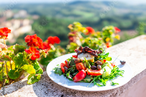Fototapeta Naklejka Na Ścianę i Meble -  Closeup of olive salad on plate on balcony terrace by red geranium flowers in garden outside in Italy in Tuscany