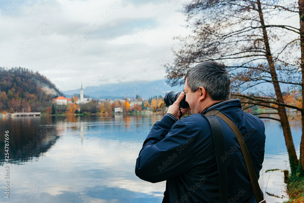 Man taking photos of Bled Lake and Church in Slovenia Man taking photos of Bled Lake and Church in Slovenia