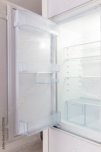 Open empty modern white kitchen refrigerator fridge inside interior vertical closeup of appliance