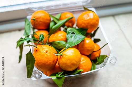 Fotografia Closeup of plastic box with many satsuma mandarin oranges on floor with vibrant