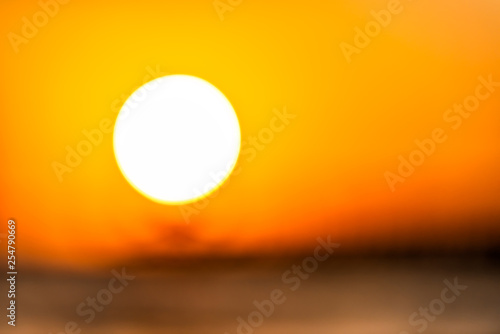 Bokeh blurry background abstract closeup of sun in Naples  Florida with orange sunset in gulf of Mexico and pier landscape on horizon