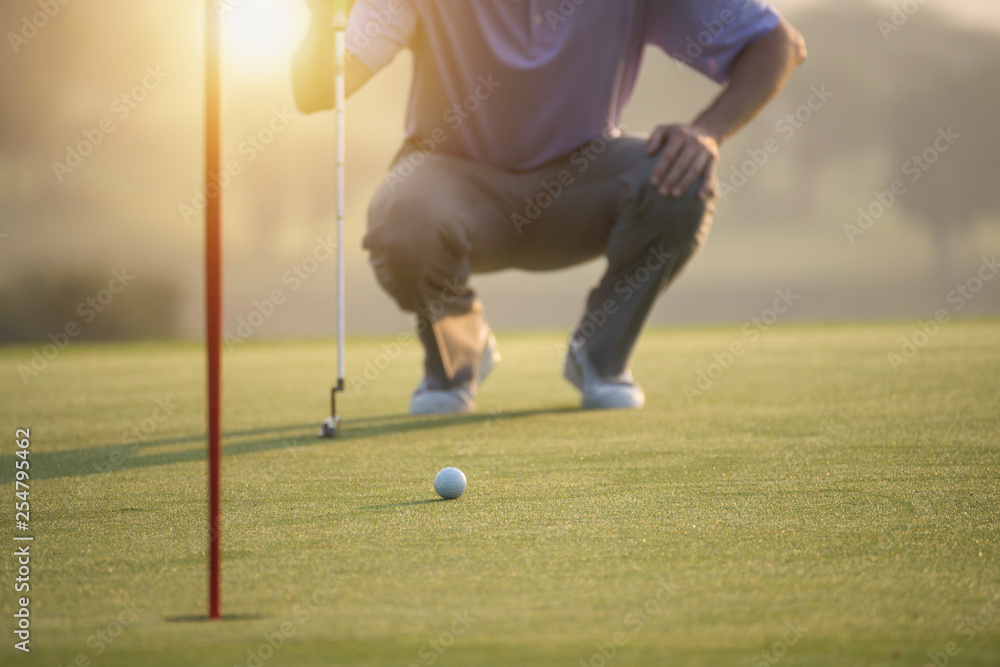 Obraz premium Golf balls on green grass with Golf holes is foreground and Golfers as a background amid the warm sunshine in the morning.