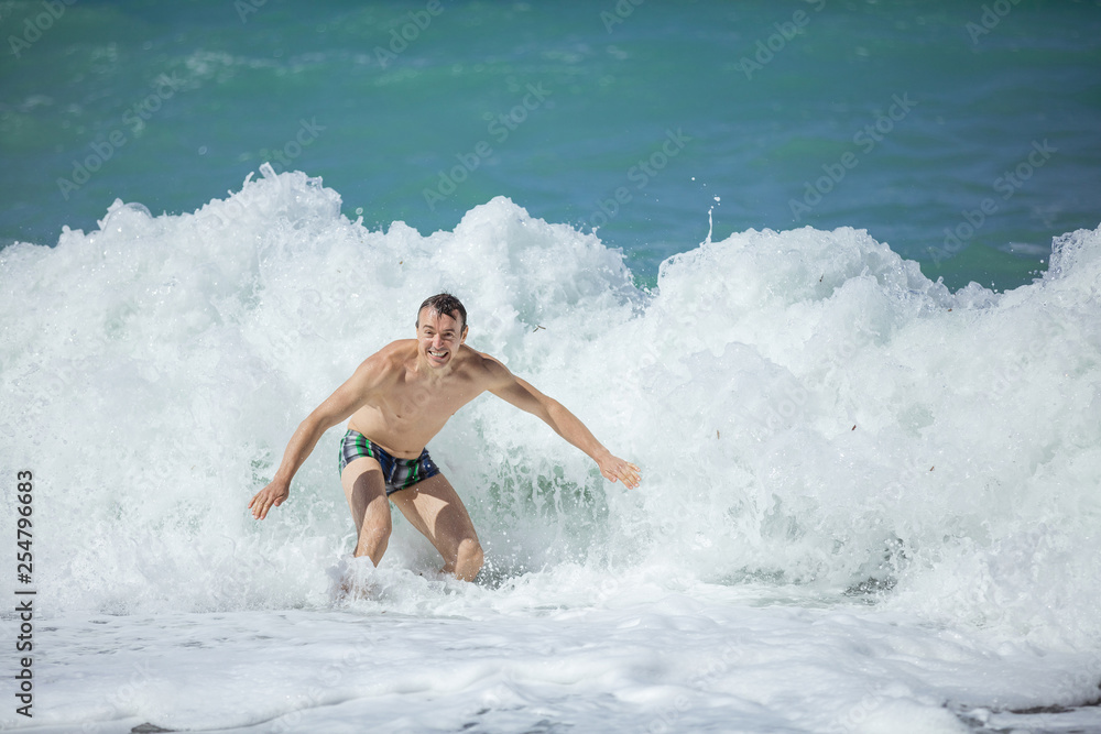 Young man enjoying high waves in rough sea