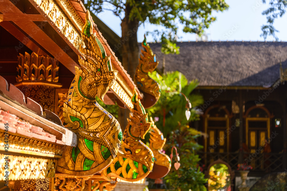 Obraz premium Asian ornament decorated detail of cornice with golden head of Naga, creature in Buddhist fairy tale, under the roof of temple in Thailand. 