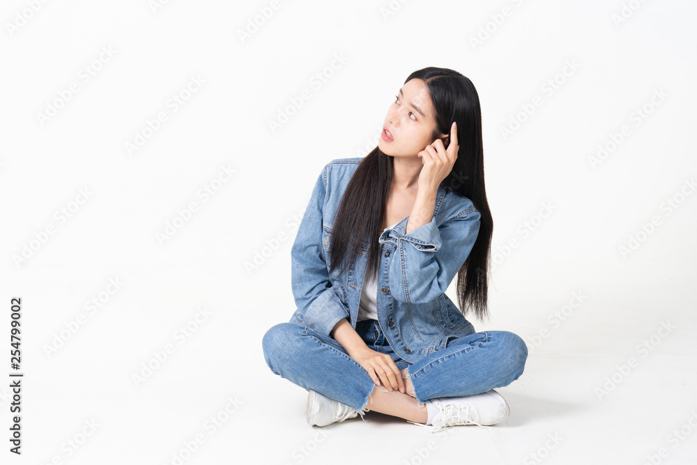 Thinking asian woman sitting on floor isolated on white background.Asian female model smiling looking up.woman pointing fingers away while sitting on a floor with legs crossed isolated Thinking asian woman sitting on floor isolated on white background.Asian female model smiling looking up.woman pointing fingers away while sitting on a floor with legs crossed isolated