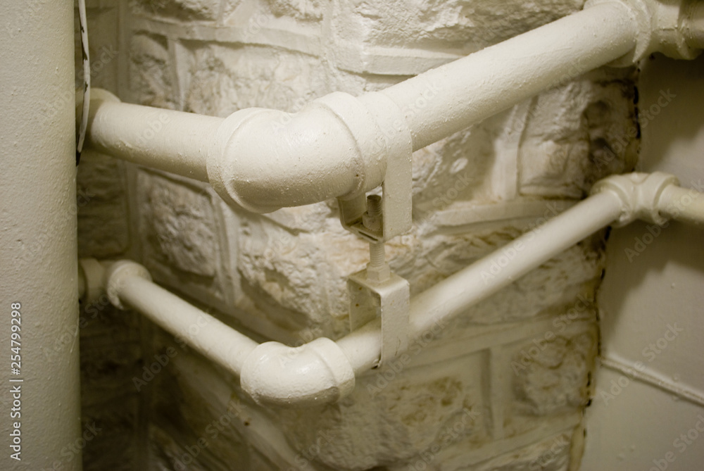 two pipes with elbow joints in stone wall