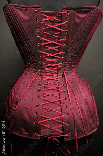 Foto Closeup of red vintage female corset on grey studio background