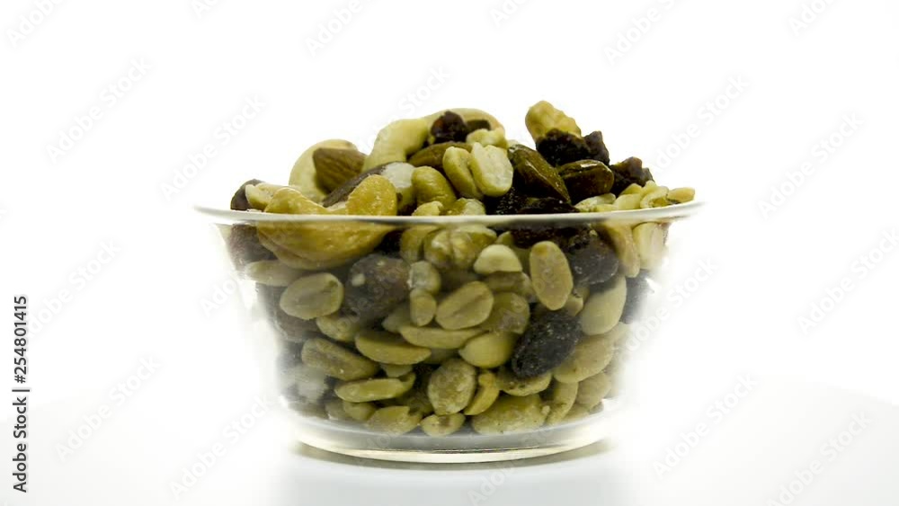 A glass bowl of mixed nuts rotating clockwise on a white background. A glass bowl of mixed nuts rotating clockwise on a white background.