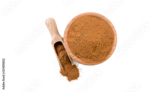 milled or ground nutmeg in wooden bowl and scoop isolated on white background. top view. Spices and food ingredients.