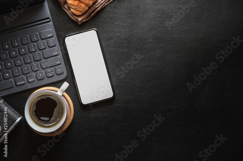 Mock up mobile phone on home office dark  leather desk and copy space