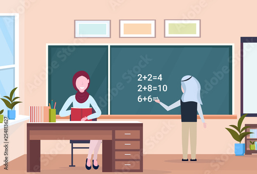 muslim arabian teacher with arab schoolboy solving math problem on chalkboard during lesson education concept modern school classroom interior full length horizontal