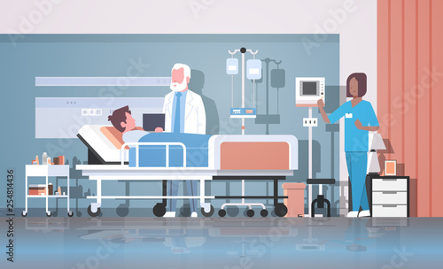 doctor and nurse visiting patient man lying bed with dropper intensive therapy ward healthcare concept hospital room interior modern medical clinic horizontal full length