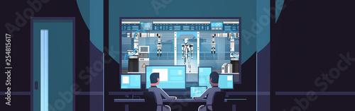 two engineers looking at monitors behind glass robot production modern factory robotic industry artificial intelligence dark office interior surveillance security system flat horizontal
