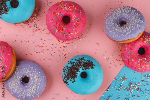 Cooking, baking and food concept - closeup multicolored glazed donuts top view. Trendy colors are blue pink and purple.