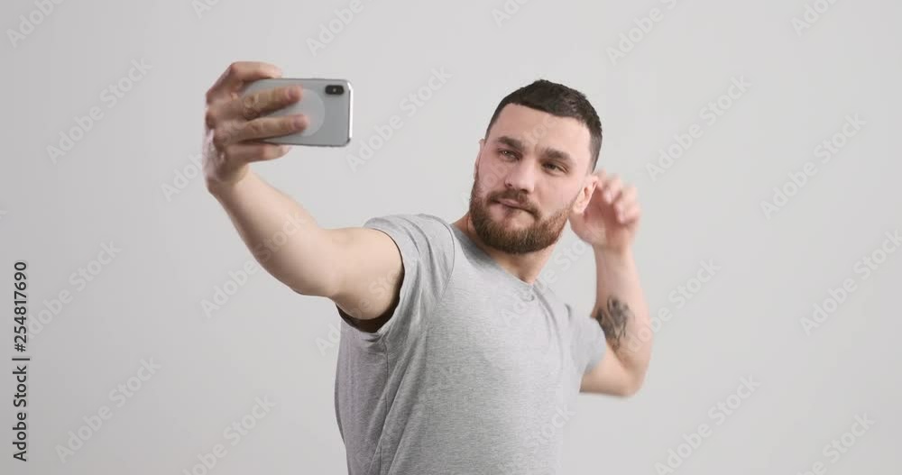 Handsome young man taking selfie in different pose using mobile phone camera Handsome young man taking selfie in different pose using mobile phone camera