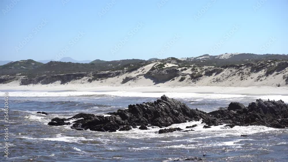 Waves hit the rocks in front of beautiful sandy beach in South Africa Waves hit the rocks in front of beautiful sandy beach in South Africa