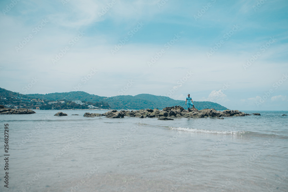 a man on a rock looking into the distance against the sea a man on a rock looking into the distance against the sea