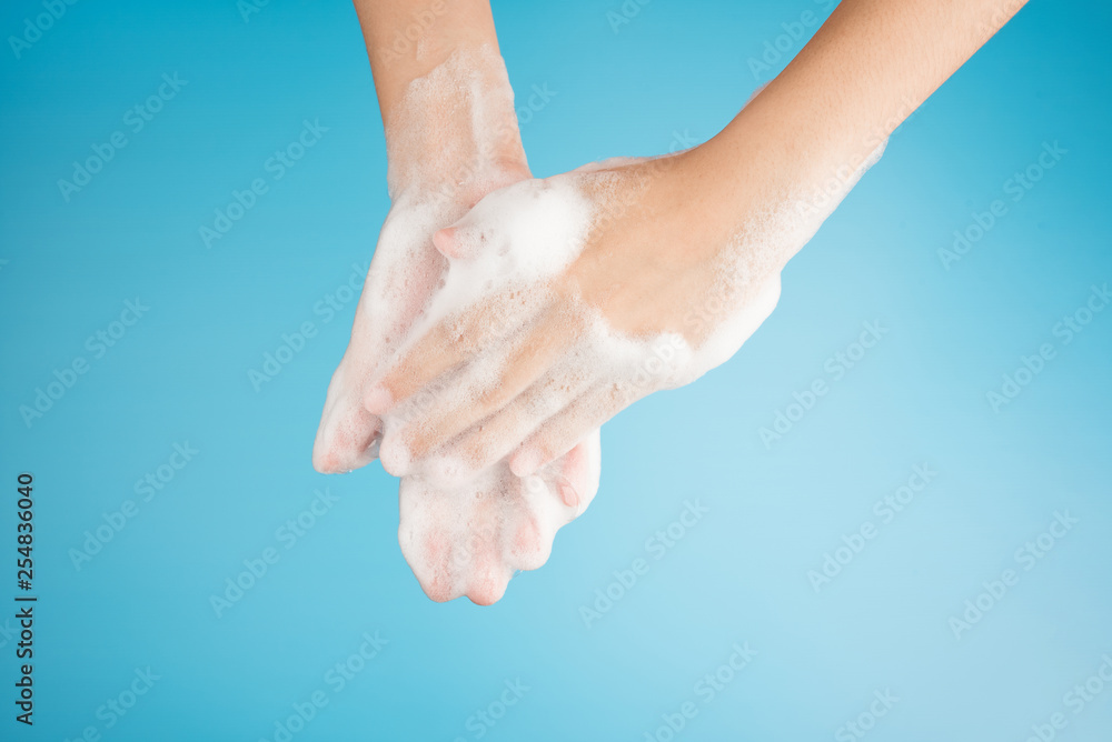 Hands female washing with bubble foam from soap on top view isolated on blue background Hands female washing with bubble foam from soap on top view isolated on blue background