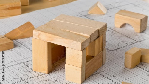 Stop motion timelapse of house built from wooden blocks on architectural building blueprint
