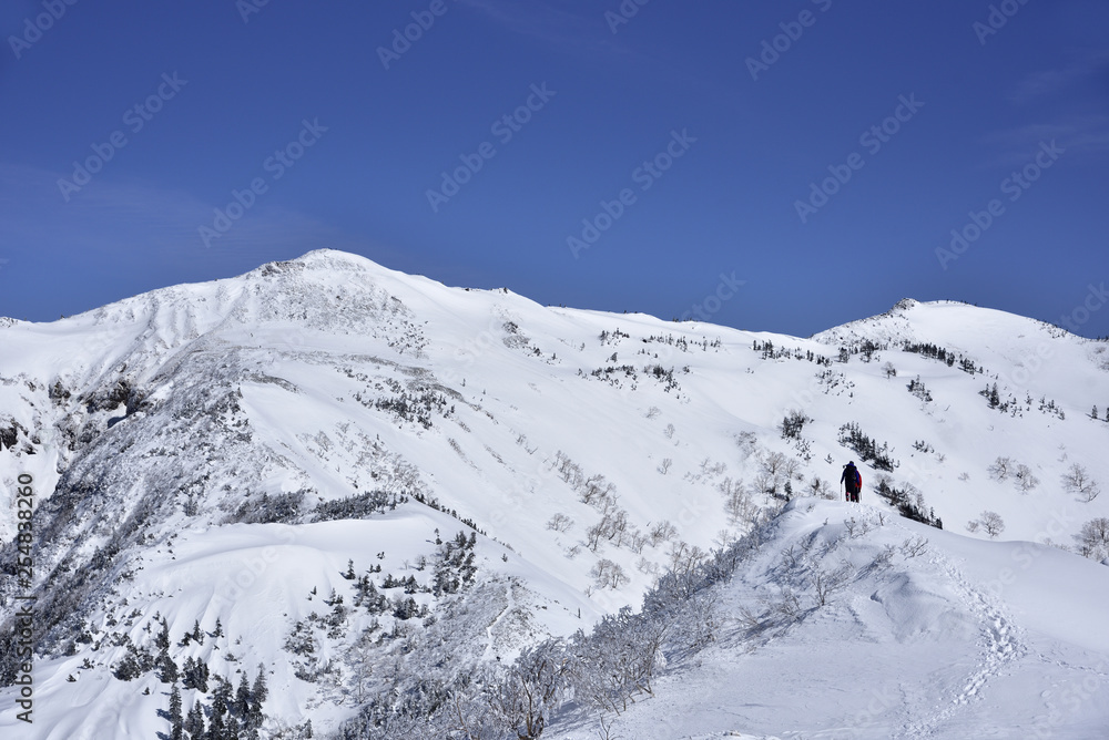 上州武尊山の山頂に向かって雪の尾根を歩く登山者。 上州武尊山の山頂に向かって雪の尾根を歩く登山者。