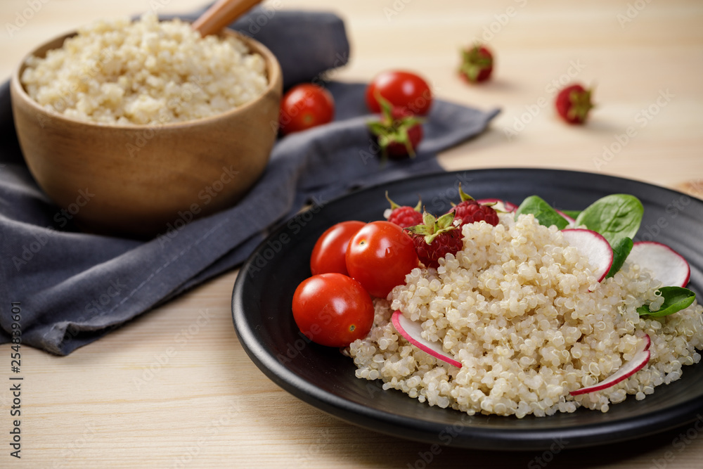 Quinoa salad with vegetables, raspberry and tomatoes on the wooden table. Super food for healthy and concept of balanced diet Quinoa salad with vegetables, raspberry and tomatoes on the wooden table. Super food for healthy and concept of balanced diet