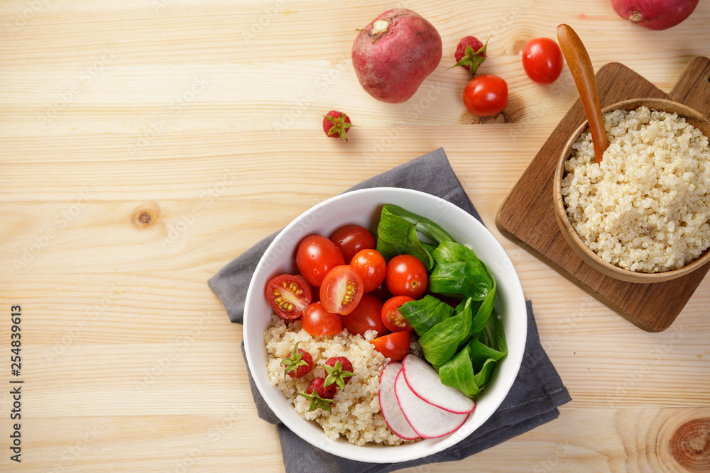 Quinoa salad with vegetables, raspberry and tomatoes on the wooden table. Super food for healthy and concept of balanced diet Quinoa salad with vegetables, raspberry and tomatoes on the wooden table. Super food for healthy and concept of balanced diet