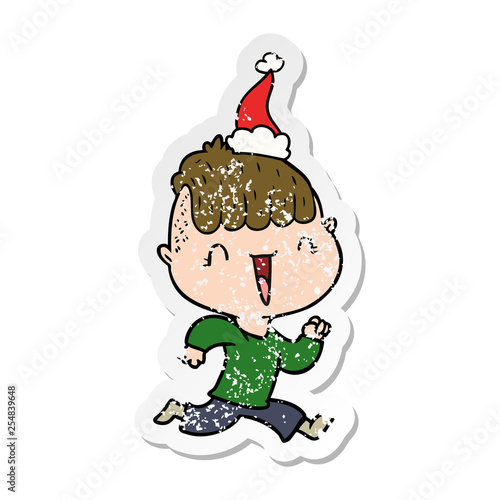 distressed sticker cartoon of a happy boy surprised wearing santa hat