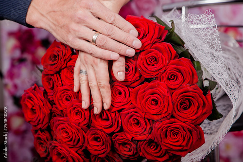 Duży bukiet czerwonych róż i dłonie zakochanej pary