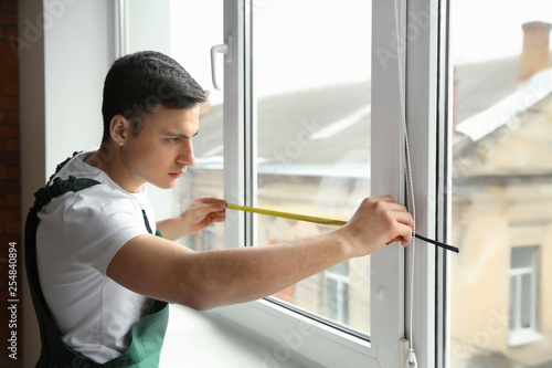 Male worker taking measurements of window in flat © Pixel-Shot