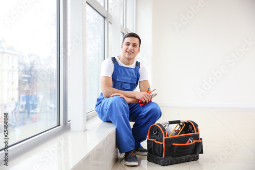 Young worker sitting on window sill in flat