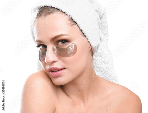 Young woman with under-eye patches on white background