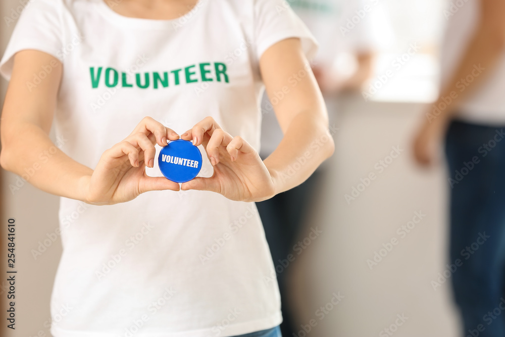 Young female volunteer with badge indoors Young female volunteer with badge indoors
