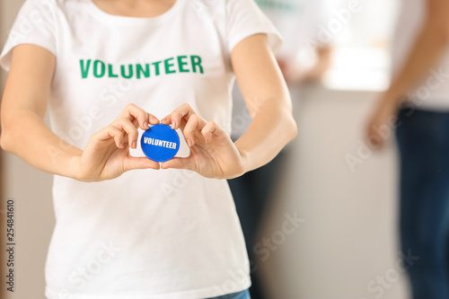 Young female volunteer with badge indoors