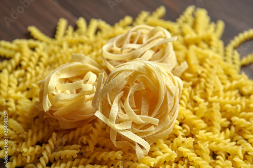 Tagliatelle pasta and spiral italian pasta on brown wooden table