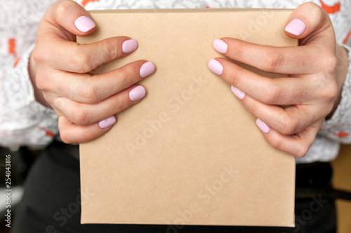 The women with manicured pink nail holding the gift box