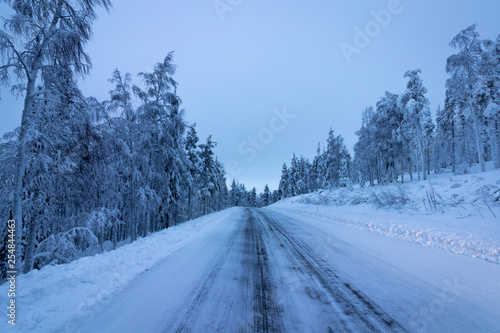 Deserted road in winter with snow covered trees in Levi, Lapland, Finland