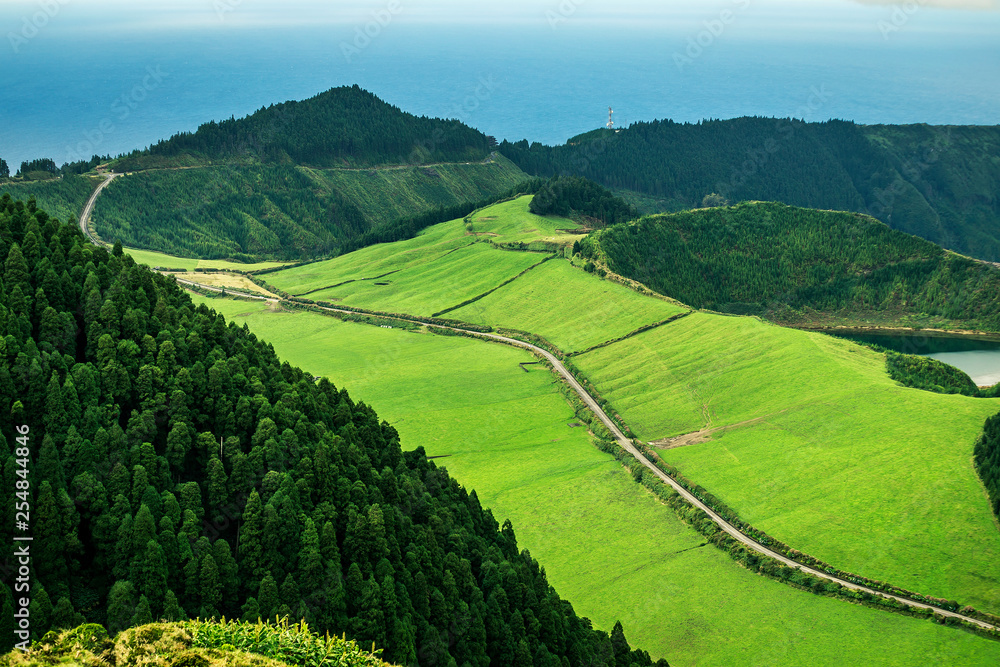Fototapeta premium Aerial view on scenic landscape of volcanic lake Sete Cidades and green fields around it. Special shape of ground. Atlantic ocean on background. Azores islands, Sao Miguel, Portugal.