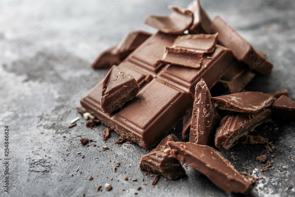 Pieces of tasty milk chocolate on grunge background Pieces of tasty milk chocolate on grunge background