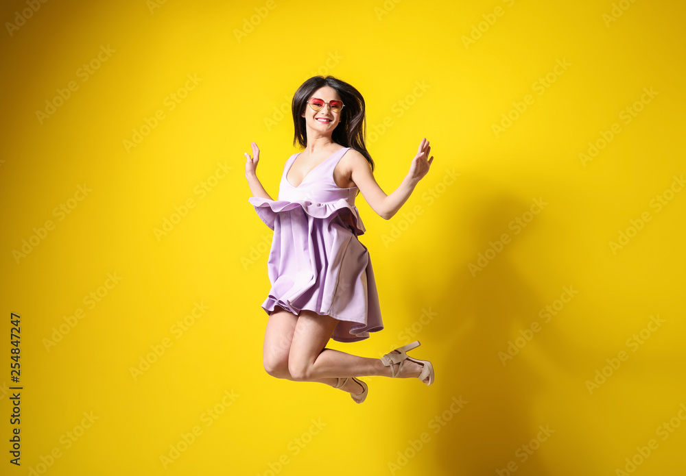 Beautiful jumping woman against color background